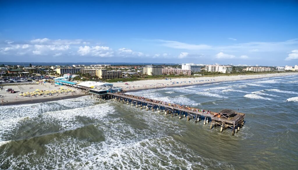 Westgate Cocoa Beach Pier as seen from a drone showing waves and crowds.
