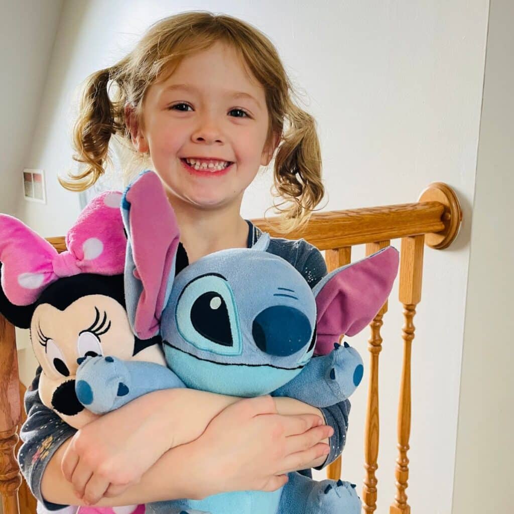 child holding minnie mouse and stitch stuffed animals